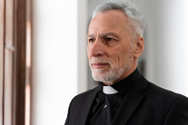 Close up smiley senior priest indoors