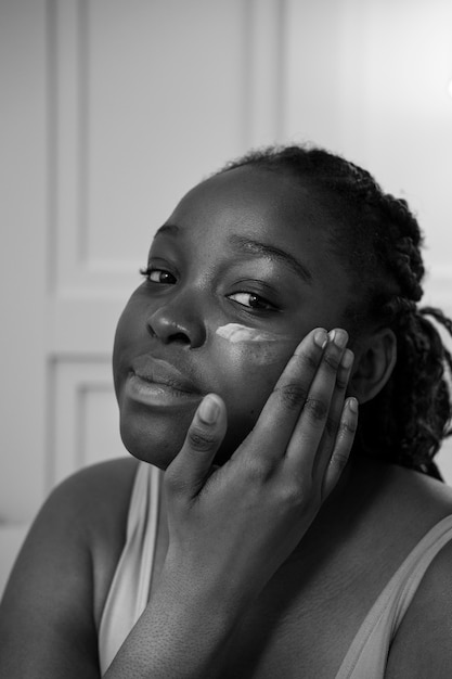 Close up smiley woman applying face cream