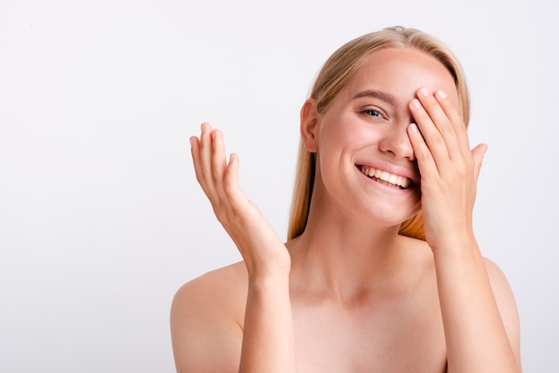 Close-up smiley woman covering her eye with one hand