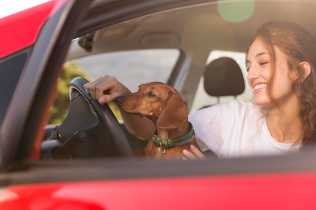 犬と一緒に運転している笑顔の女性をクローズアップ