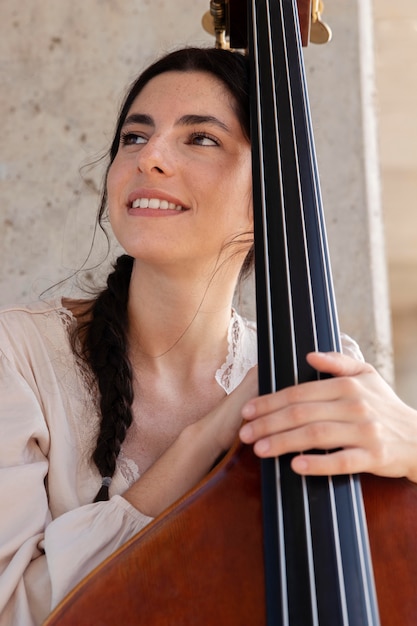 Free photo close up smiley woman holding double bass