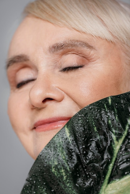 Free photo close-up smiley woman holding leaf