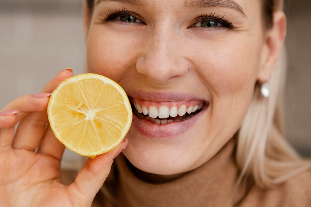 Close up smiley woman holding lemon slice