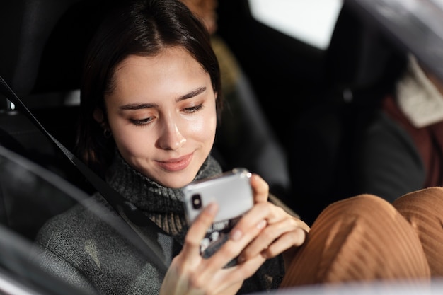 スマートフォンを持っている笑顔の女性を閉じる