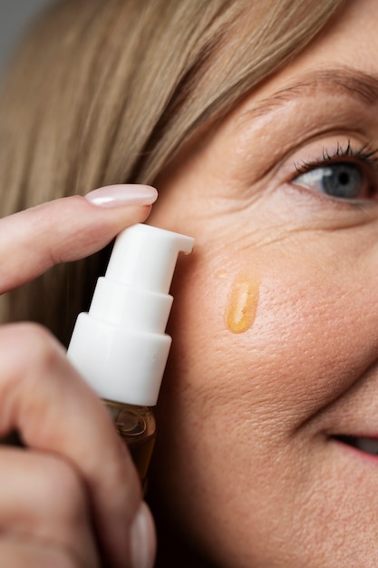 Free photo close up smiley woman using serum