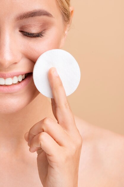 Close-up smiley woman with cotton pad 