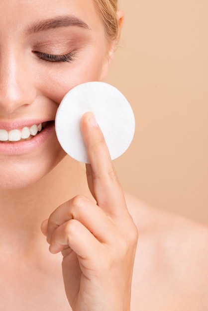 Close-up smiley woman with cotton pad 