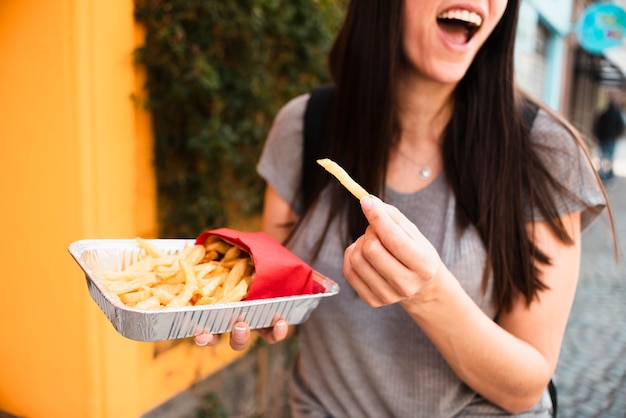 Donna sorridente di primo piano con patatine fritte