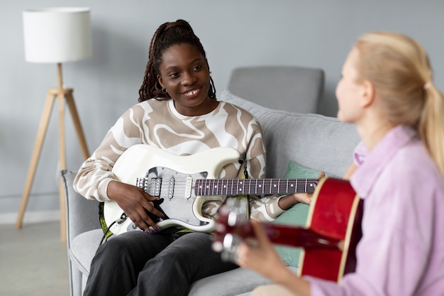 Close up smiley women playing guitar at home