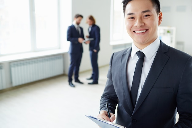 Close-up of smiling businessman with co-workers background