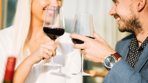 Close-up of smiling couple toasting red wine glasses