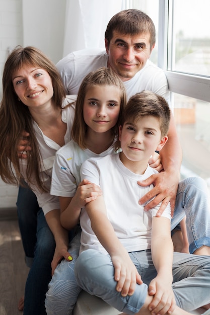 Close-up of smiling family sitting on window sill at home