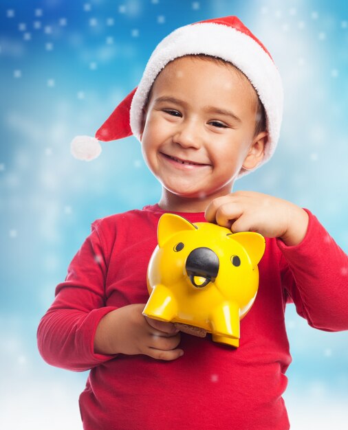 Close-up of smiling kid with his yellow piggybank