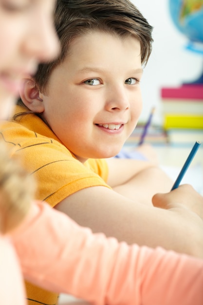 Close-up of smiling little boy with a pencil