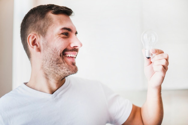 Close-up of smiling male looking at light bulb