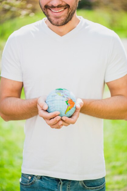 Close-up of smiling man holding globe in hand