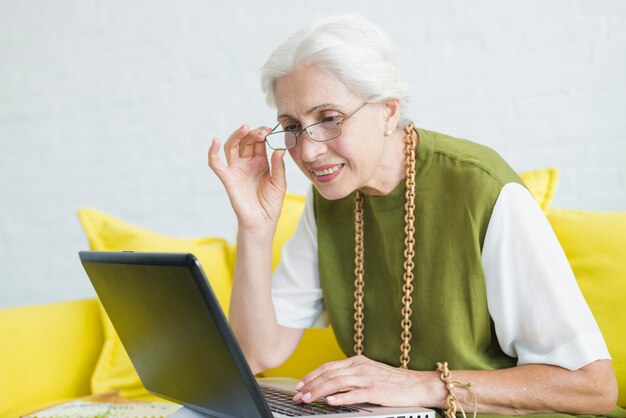 Close-up of smiling senior woman looking at laptop