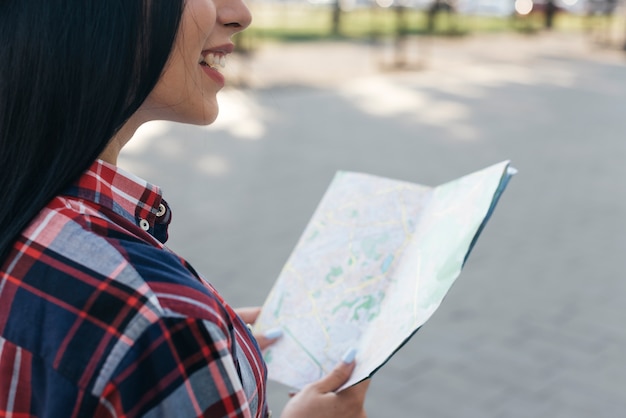 Foto gratuita primo piano della mappa sorridente della tenuta della donna che sta sulla via