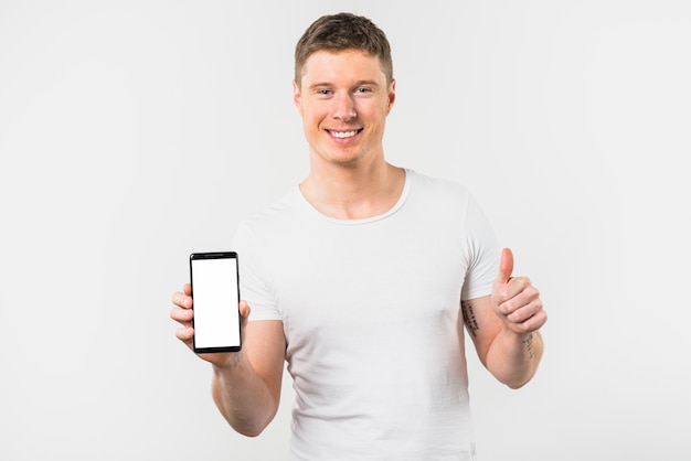 Крупный план улыбающегося молодого человека, держащего мобильный телефон в руке, показывая большой палец вверх знак