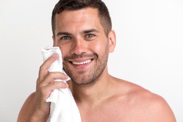Foto gratuita primo piano del giovane sorridente che pulisce fronte con l'asciugamano che esamina macchina fotografica