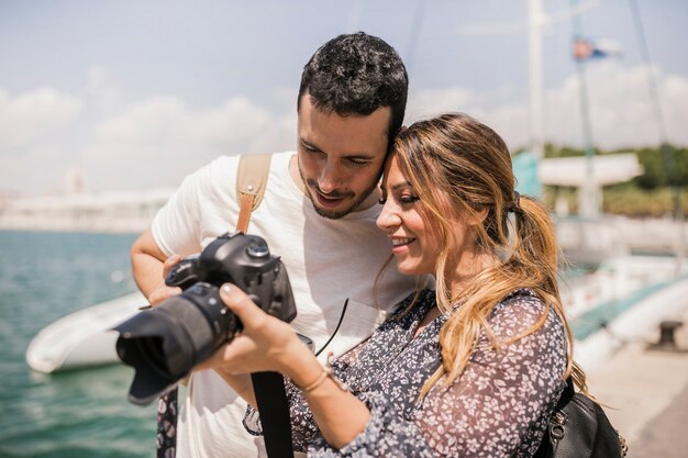 Close-up of smiling young tourist couple looking at slur camera