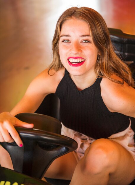 Close-up of smiling young woman sitting in bumper car