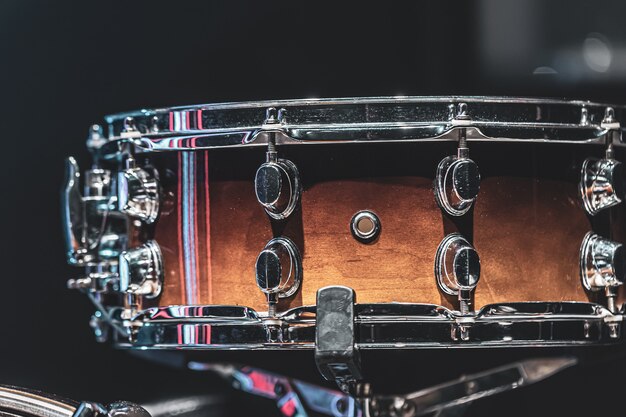 Close-up of a snare drum, percussion instrument on a dark background.