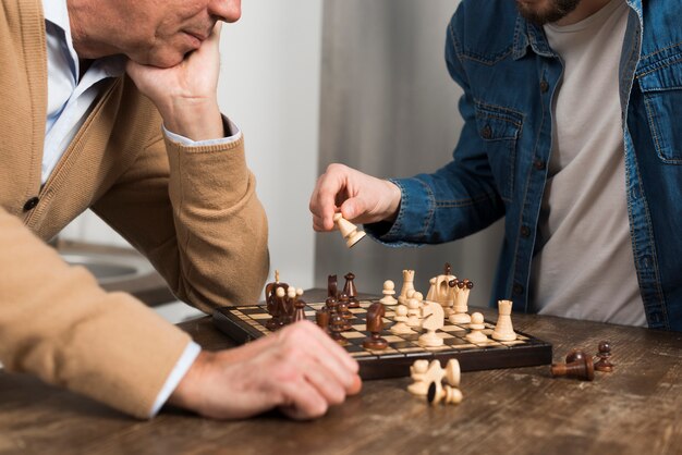 Крупным планом сын и отец играют в шахматы