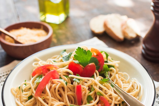 Close-up di spaghetti con pomodori e foglie di coriandolo sul piatto