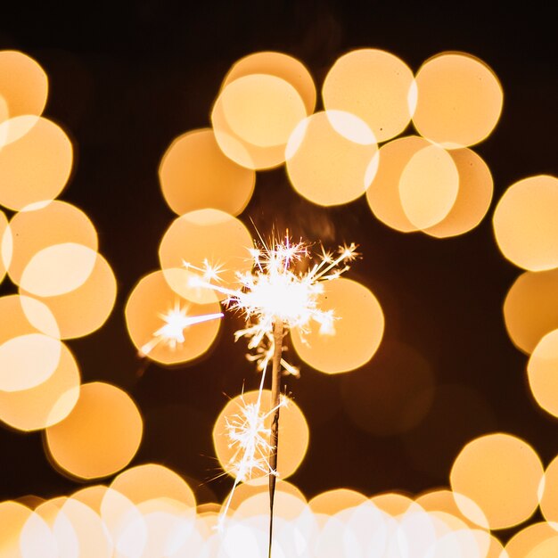 Close-up sparkler near abstract lights