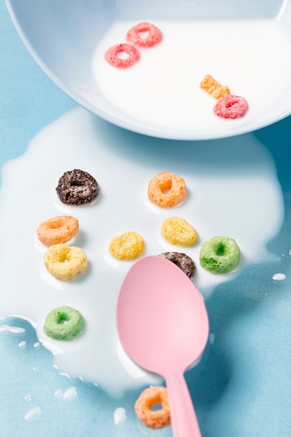 Close-up spilled milk and cereals all over the table and pink spoon