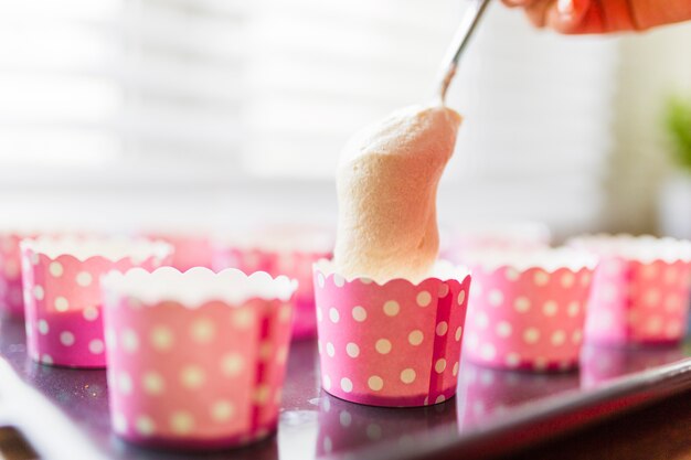 Close-up spoon and pink cups with batter