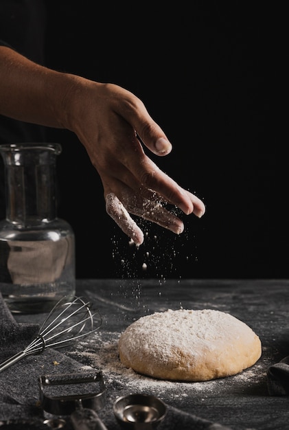 Free photo close-up spreading flour on top of dough