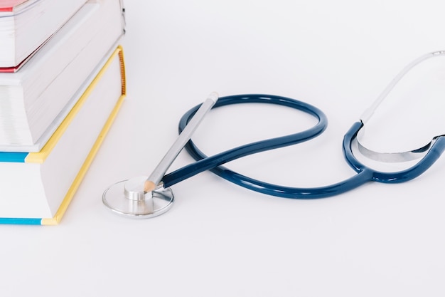 Close-up of stacked books and stethoscope on white backdrop