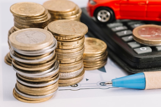 Close-up of stacked coins; pen and calculator