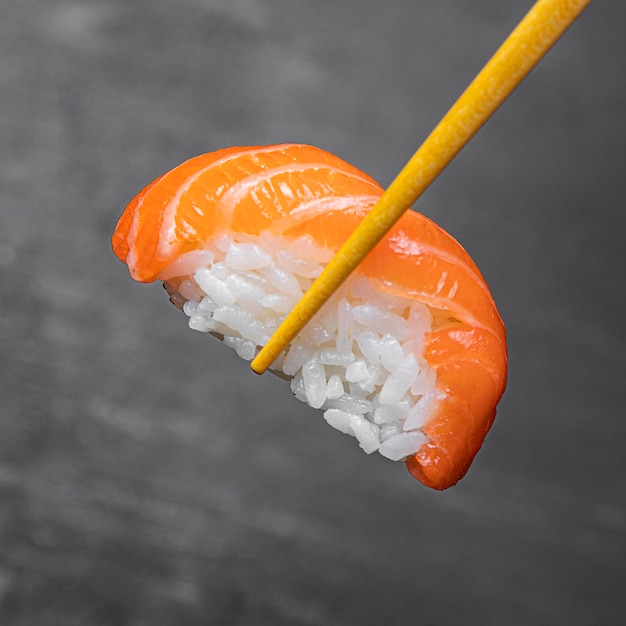 Close-up sticks holding tasty sushi