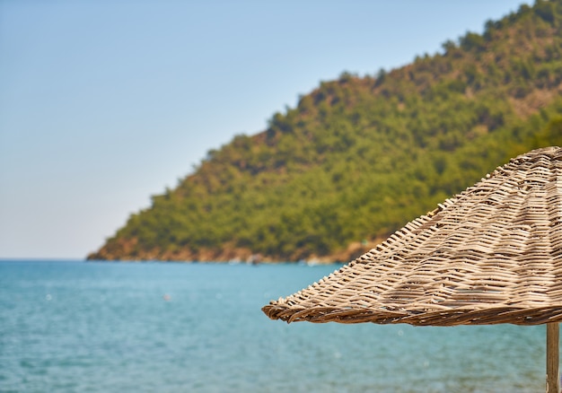 Close-up of straw umbrella with blurred mountain background