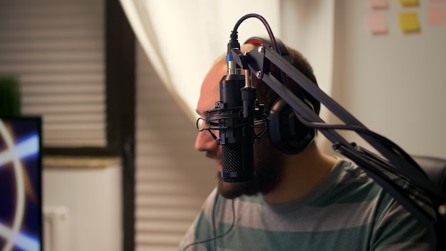 Close-up of streamer man talking into microphone with other players during space shooter tournament