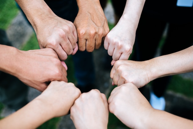 Close up of students standing hands making fist bump gesture.