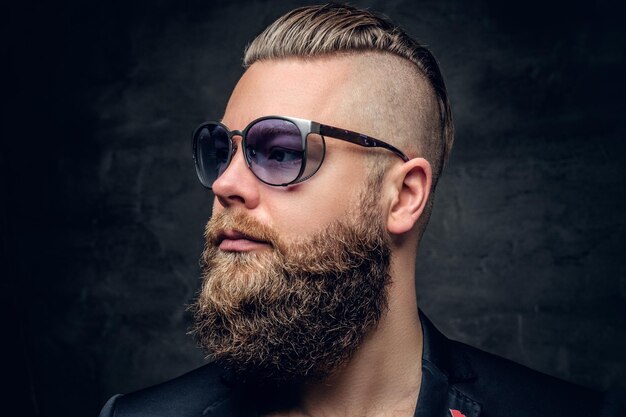 Close up studio portrait of bearded male in fashionable purple sunglasses.