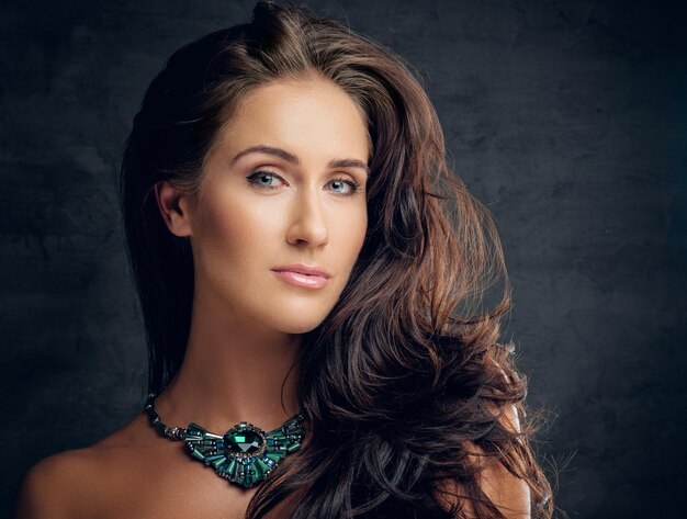 Close up studio portrait of brunette female with costly necklace.