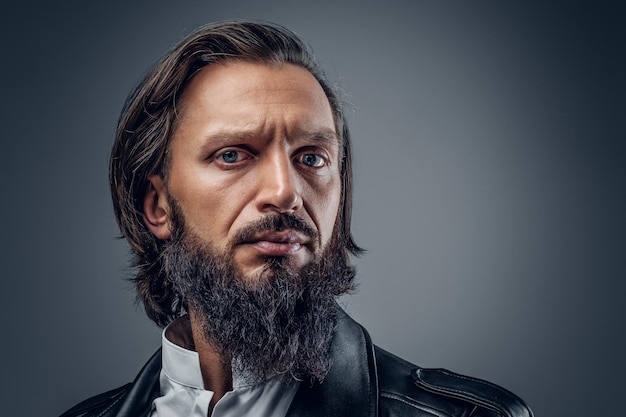 Close up studio portrait of serious, bearded male on grey background.