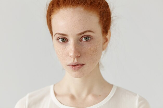 Close up studio shot of beautiful charming redhead European model with healthy freckled skin