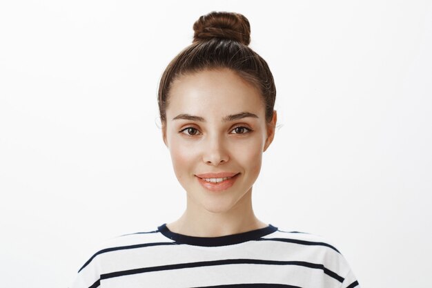 Close-up of stylish attractive girl with hairbun smiling and looking hopeful