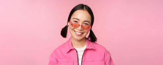 Close up of stylish korean girl in sunglasses smiling happy posing against pink background People face concept