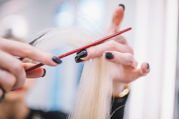 Close-up of stylist cutting fair hair