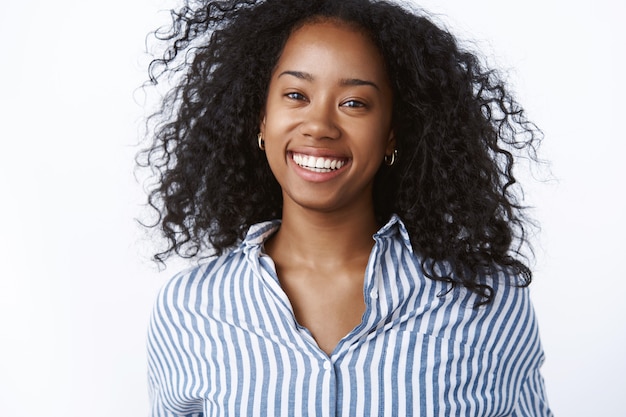Close-up successful happy satisfied busiensswoman smiling broadly feeling carefree delight enjoying wellbeing, curly hair floating air grinning sincere, have fun posing white wall
