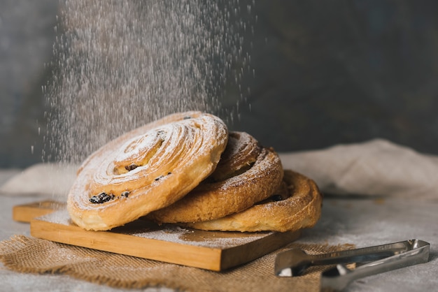 Close-up of sugar dusting on baked cinnamon buns over the chopping board