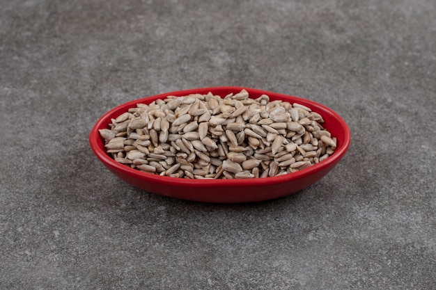 Close up of sunflower seeds in red bowl over grey surface