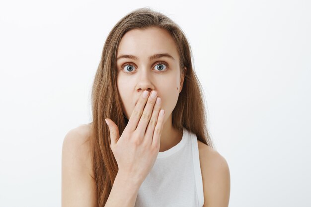 Close-up of surprised and amazed blond girl gasping, looking wondered